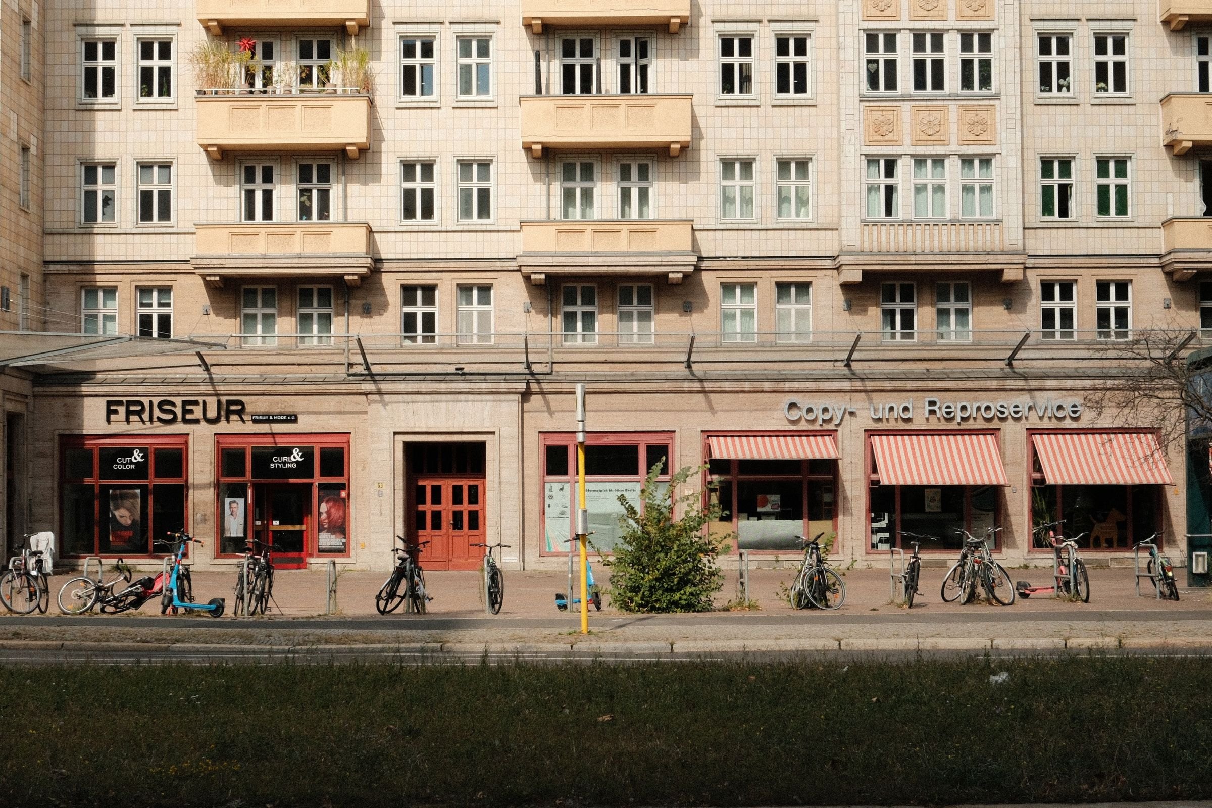 Altbaufassade mit kleinen Läden, davor eine Reihe abgestellter Fahrräder