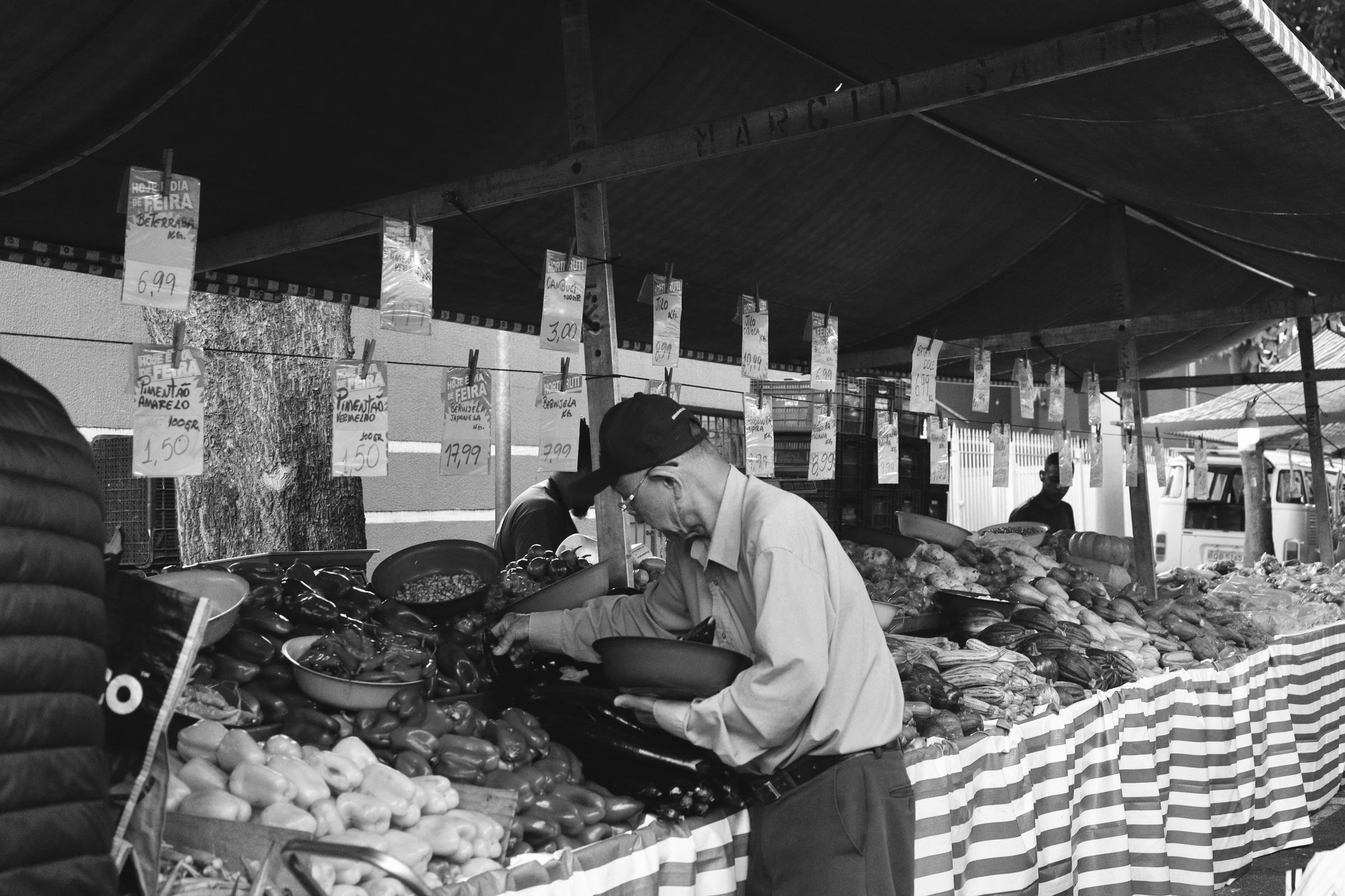 Händler sortiert Gemüse an einem Marktstand, Schwarzweißfoto