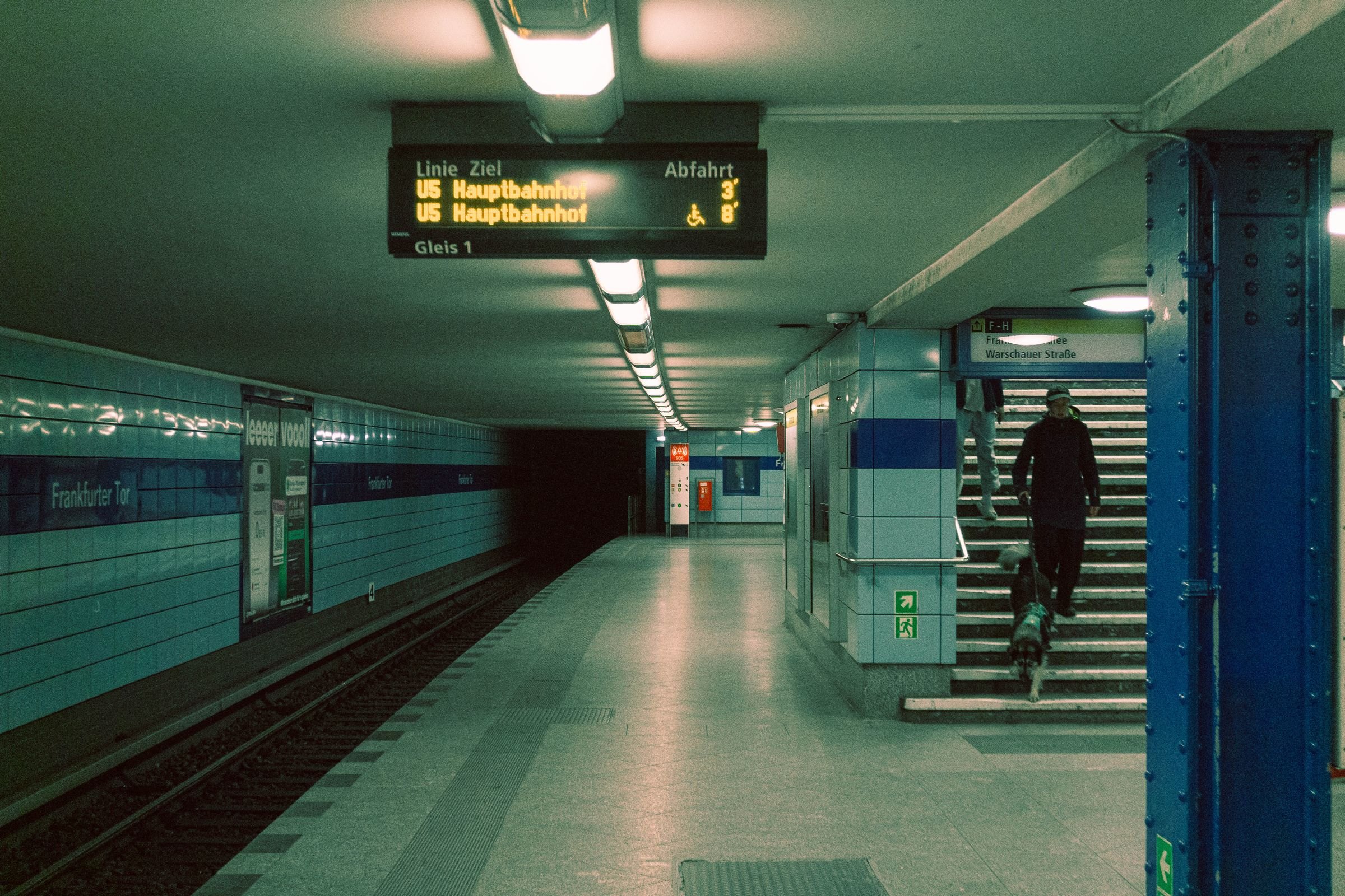 Berliner U-Bahnhof, eine Person mit Hund kommt die Treppe herunter